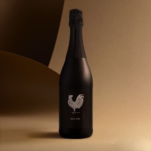 Eine dunkle, matte Champagnerflasche mit einem schwarzen Etikett, auf dem ein weißer Hahn und der Schriftzug "Black River" abgebildet sind, steht vor einem Hintergrund mit Gold- und Braun-Verlauf.