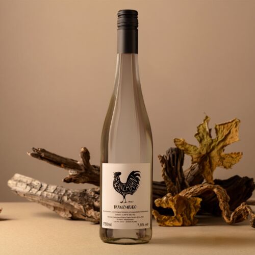 Eine durchsichtige Weinflasche mit schwarzem Schraubverschluss und einem Etikett mit einem Hahn vor getrockneten Zweigen und Blättern auf einem beigen Hintergrund. Die Flasche enthält 750 ml mit 7,5 % Alkohol.