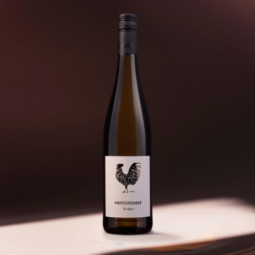 Eine hohe Weinflasche mit dunklem Verschluss und weißem Etikett, auf dem ein schwarzer Hahn und der Text "Weissburgunder Trocken" abgebildet sind, steht auf einer sanft beleuchteten Fläche vor einem dunklen, verschwommenen Hintergrund.